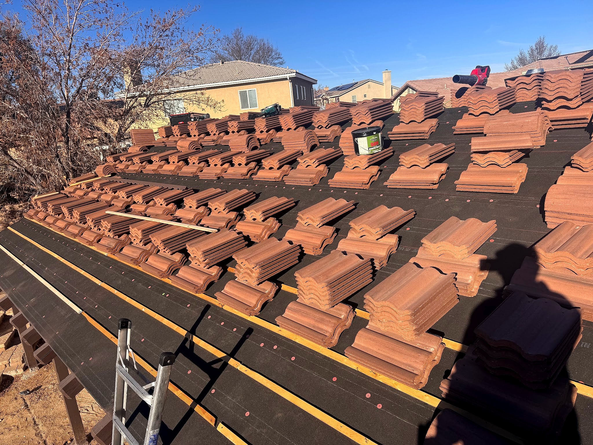 Terracotta concrete roof tiles stacked on battens over black underlayment